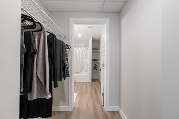 A hallway with a white door and a rack of clothes.